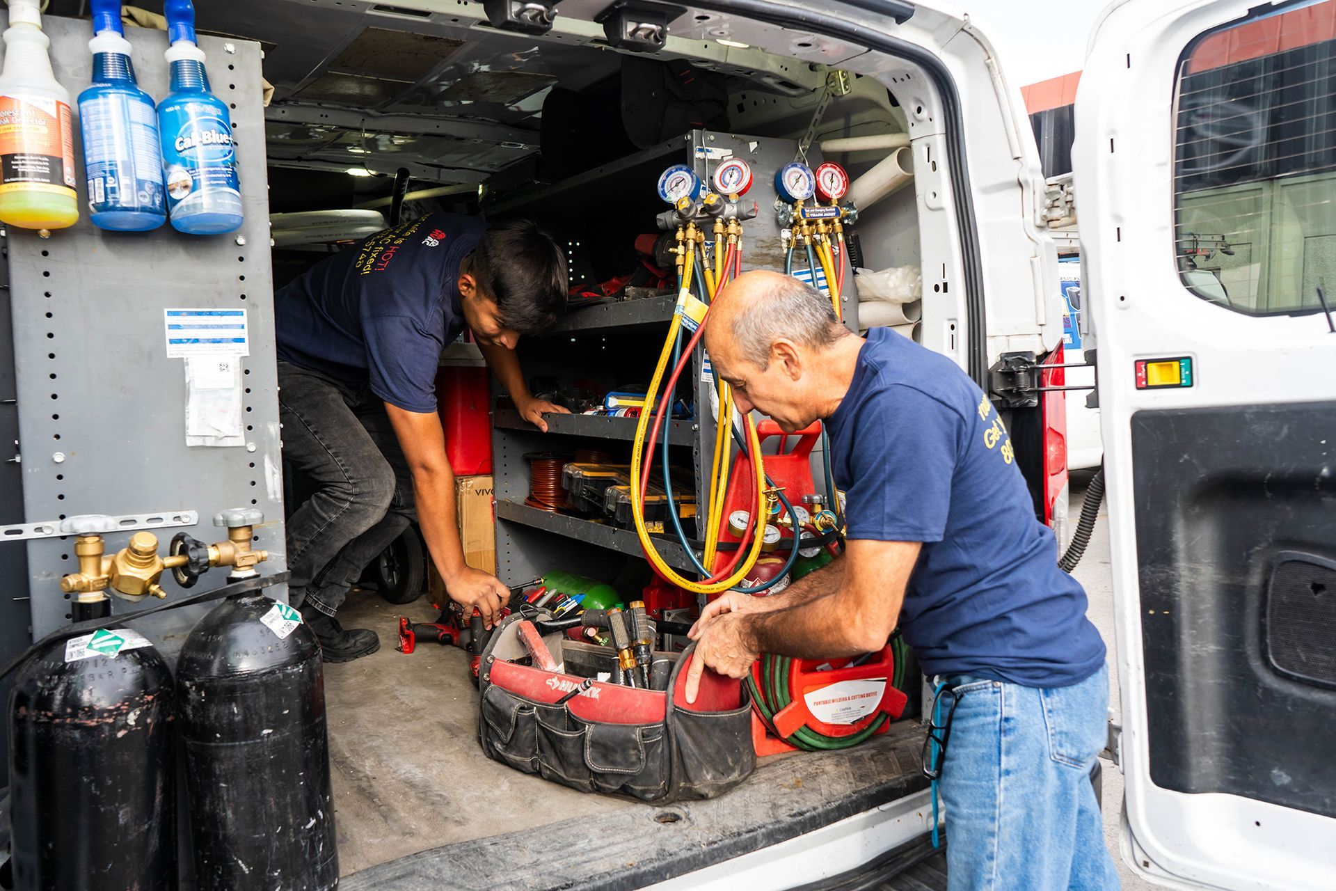 Two Lucas Heating & Air technician in an open service van, preparing tools.