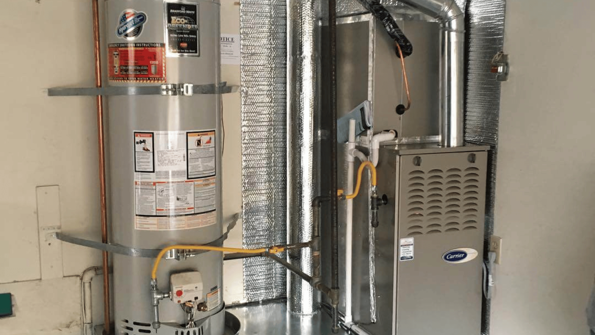 A water heater is sitting next to a furnace in a room.