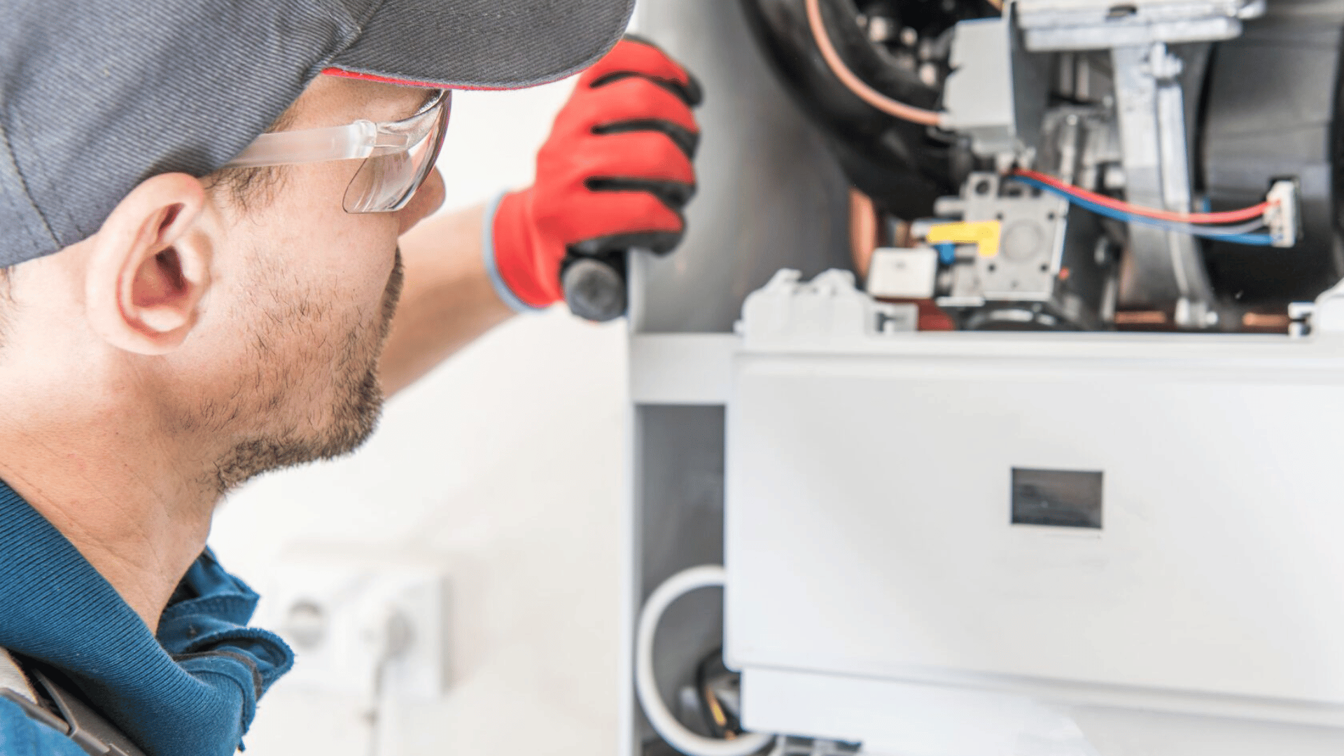 A man is working on a boiler with a flashlight.