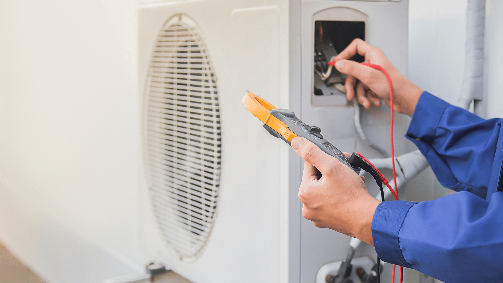A man is working on an air conditioner with a multimeter.