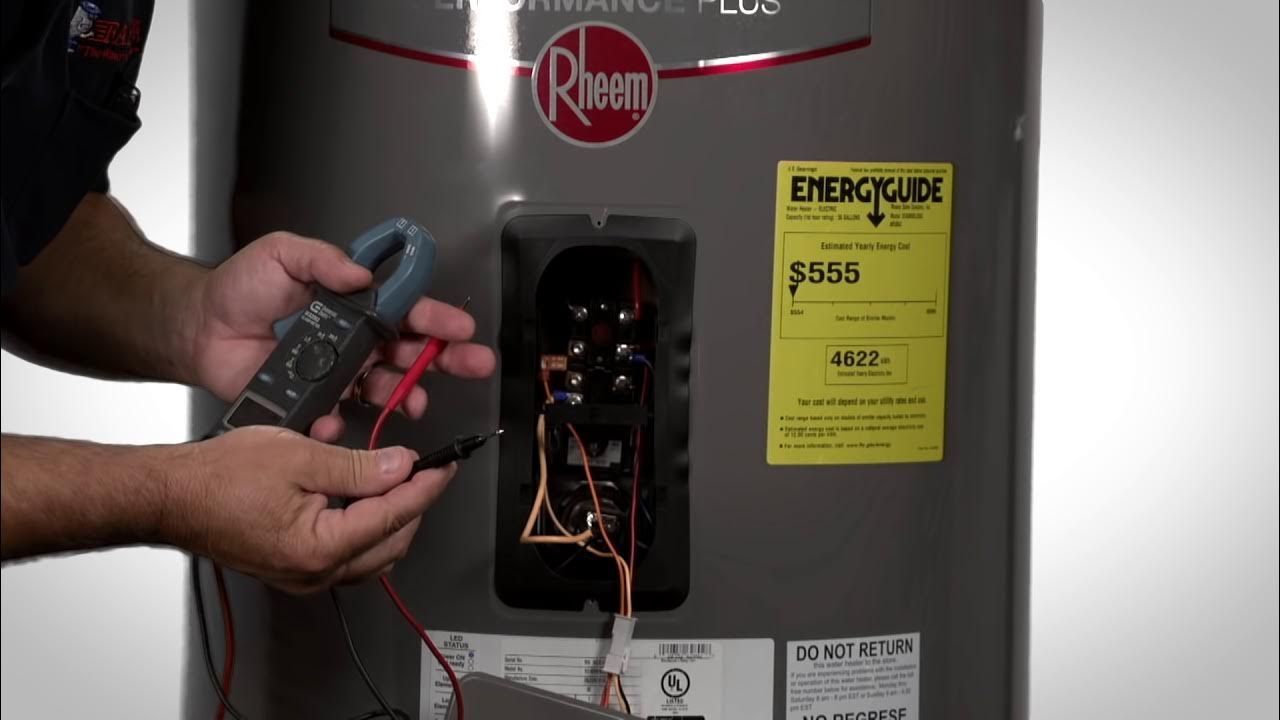 A man is holding a thermometer next to a water heater.