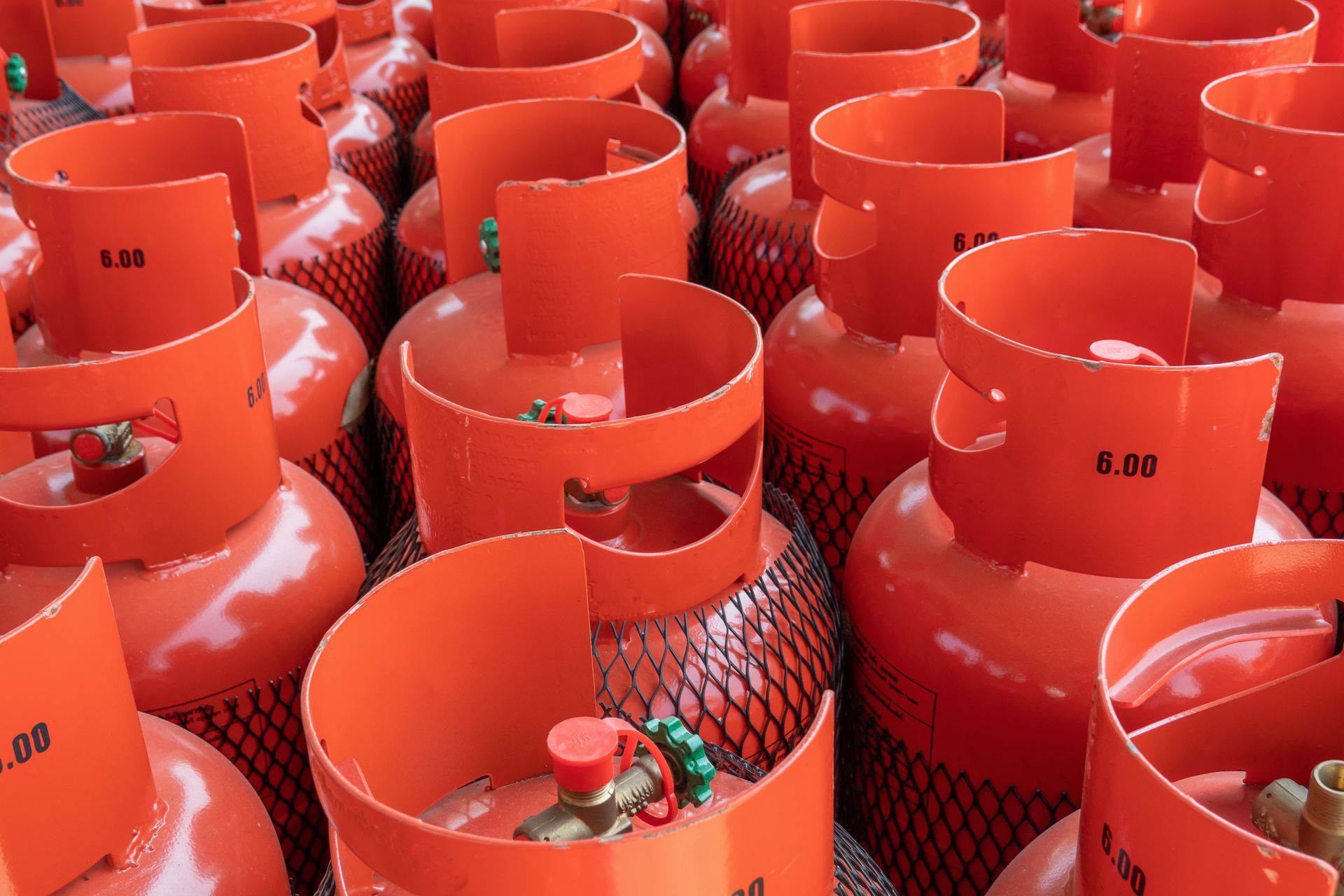 Rows of orange gas bottles are placed on the ground.