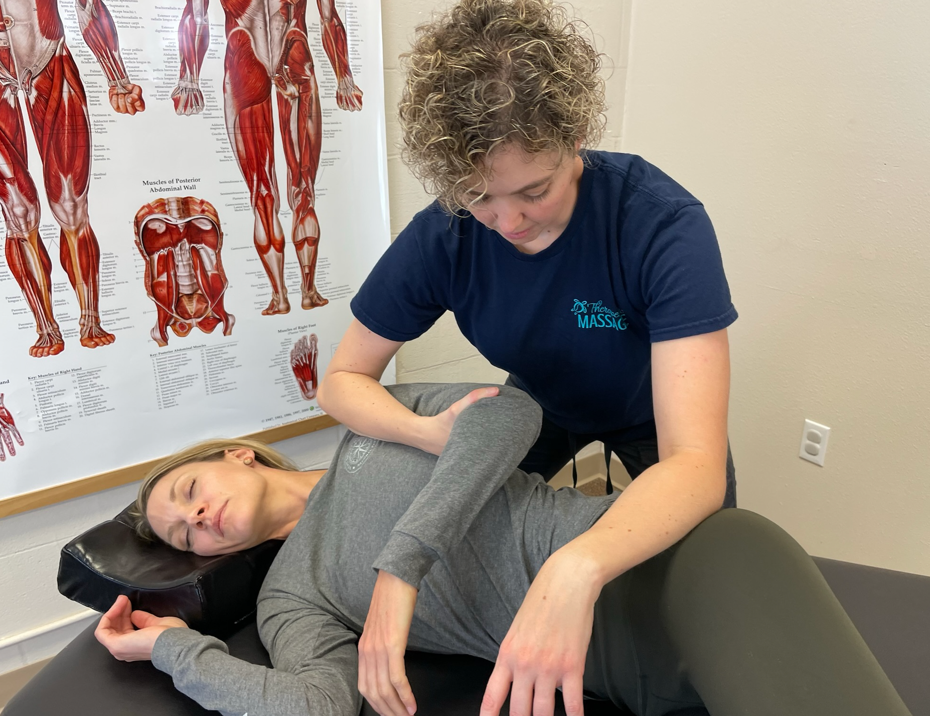 A woman is laying on a table getting a massage from a woman.