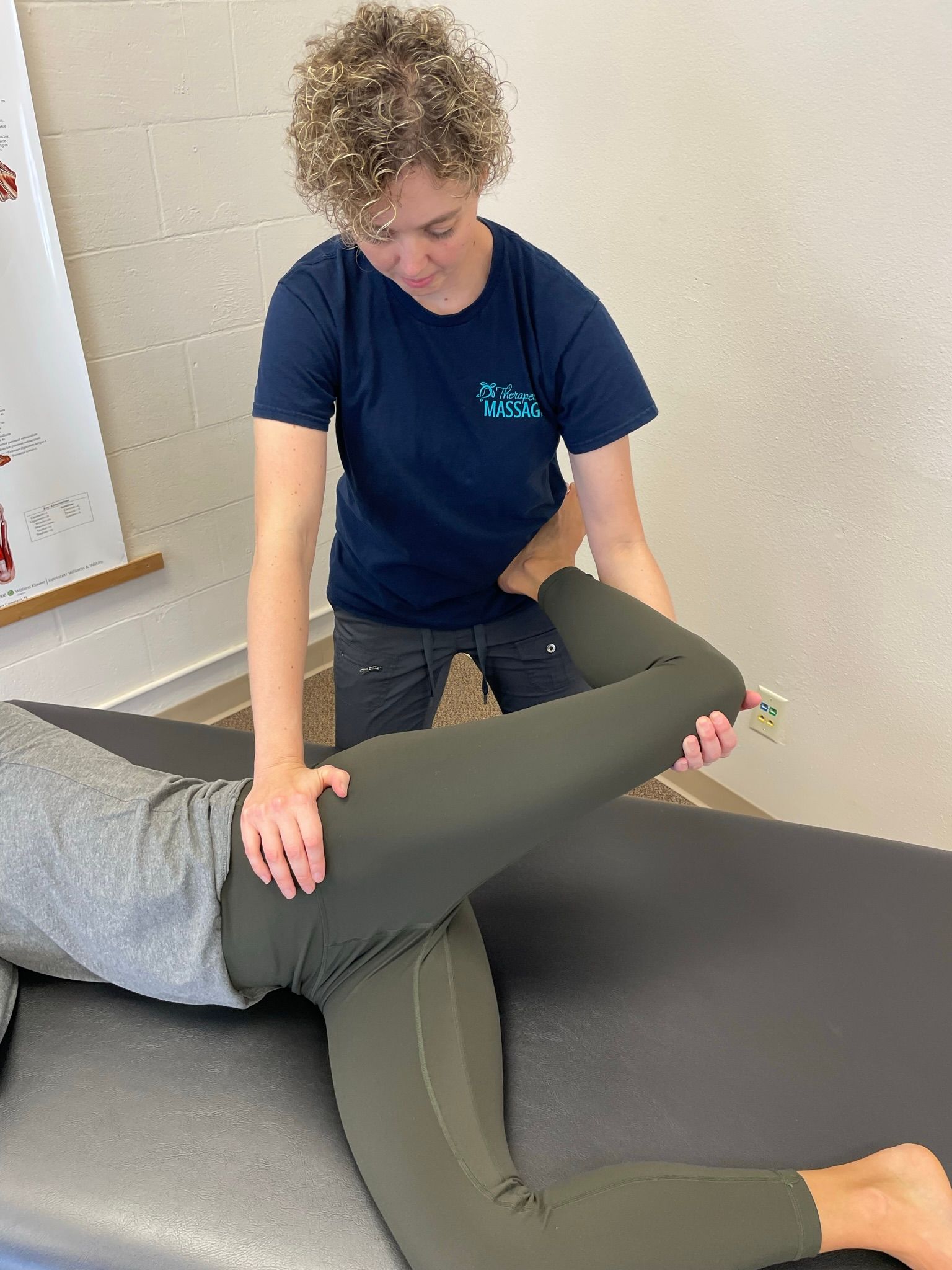 A woman is stretching a patient 's leg on a table.