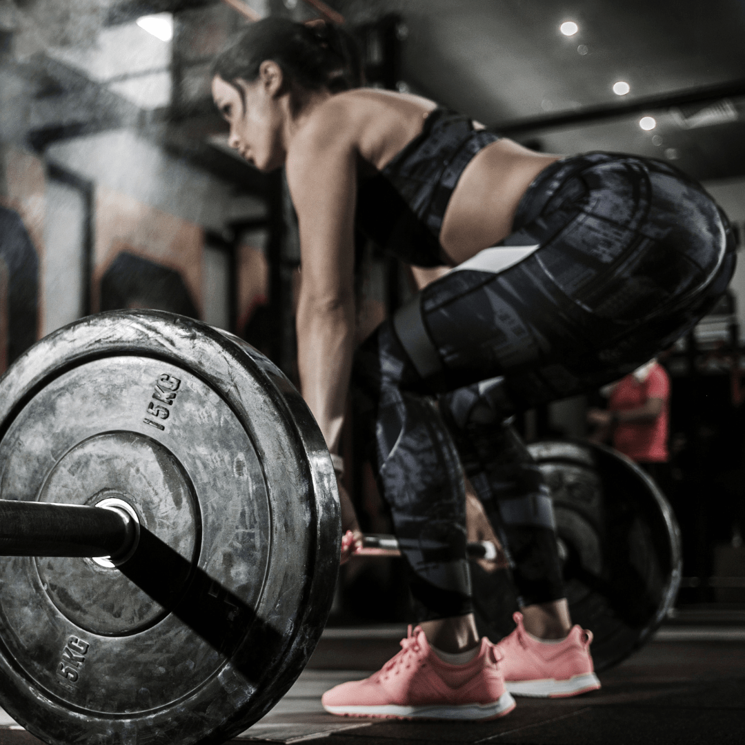 A woman is lifting a barbell in a gym.