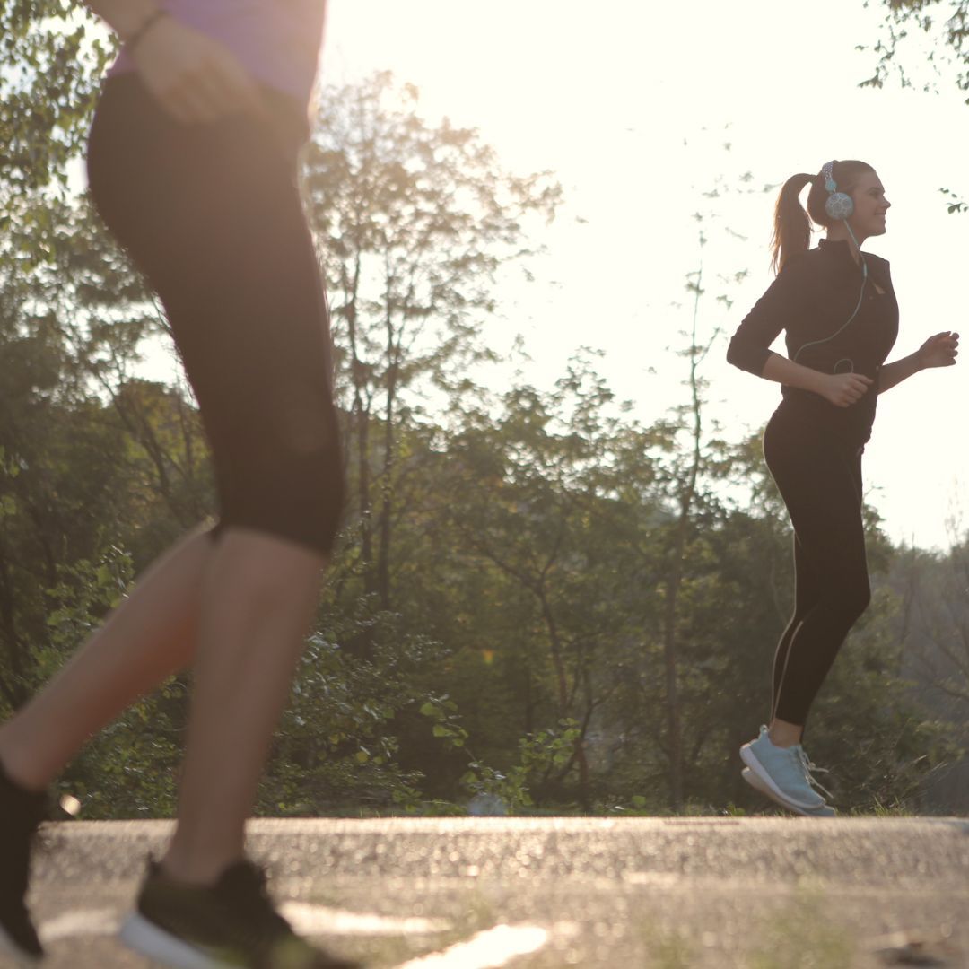 A woman wearing headphones is running next to another woman