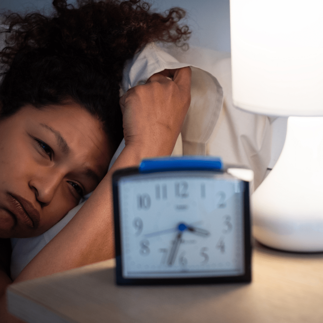 a woman laying in bed next to an alarm clock that shows the time as 7:55