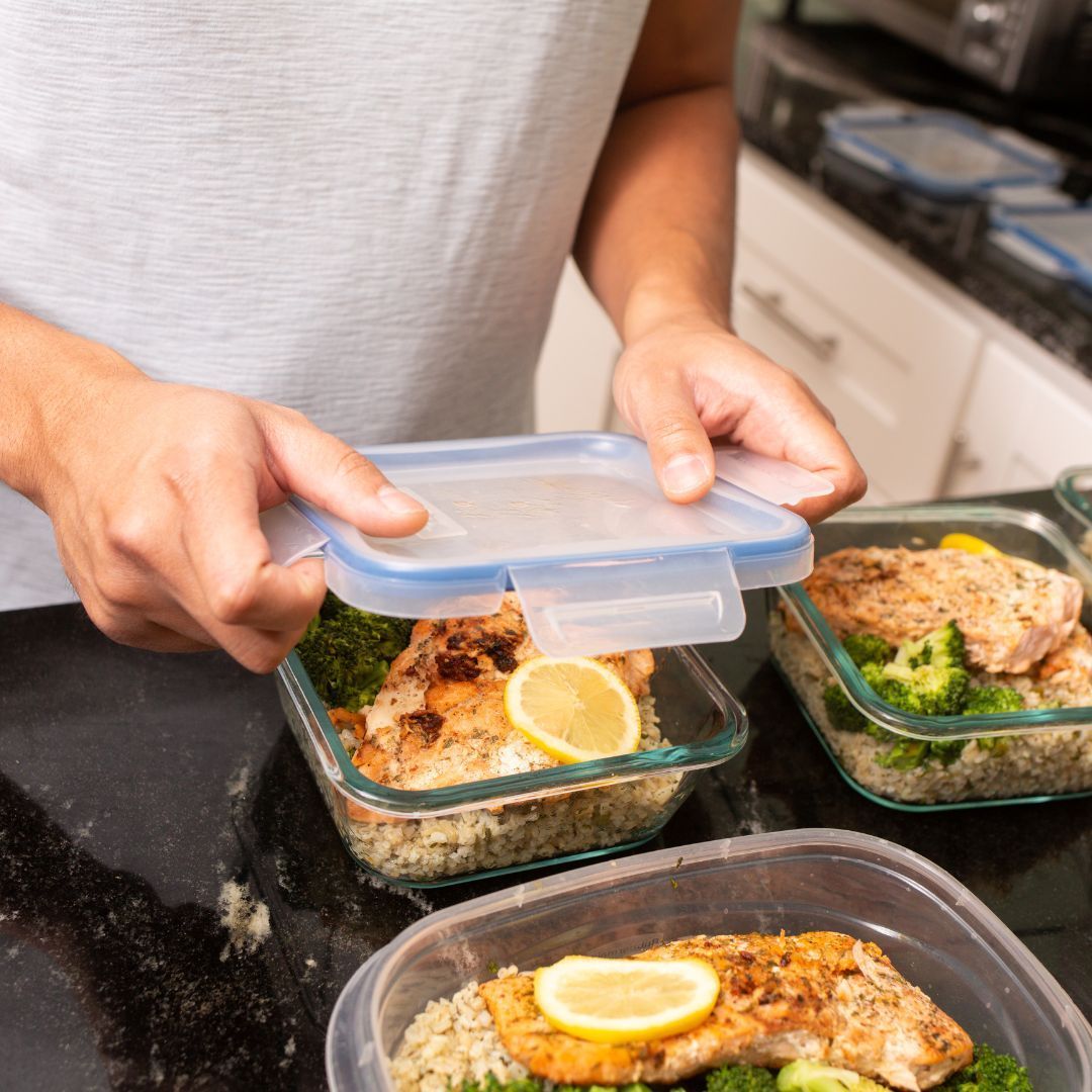 A man is putting food in a glass container on a counter.