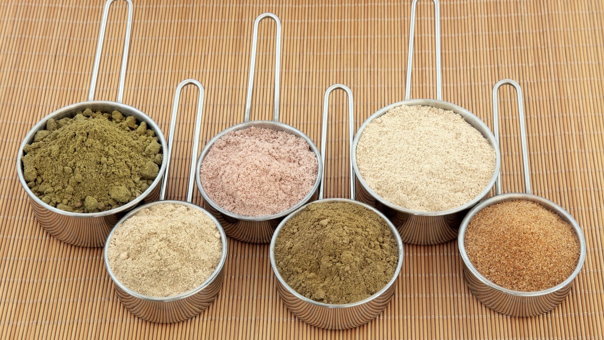 a group of measuring cups filled with different types of spices .