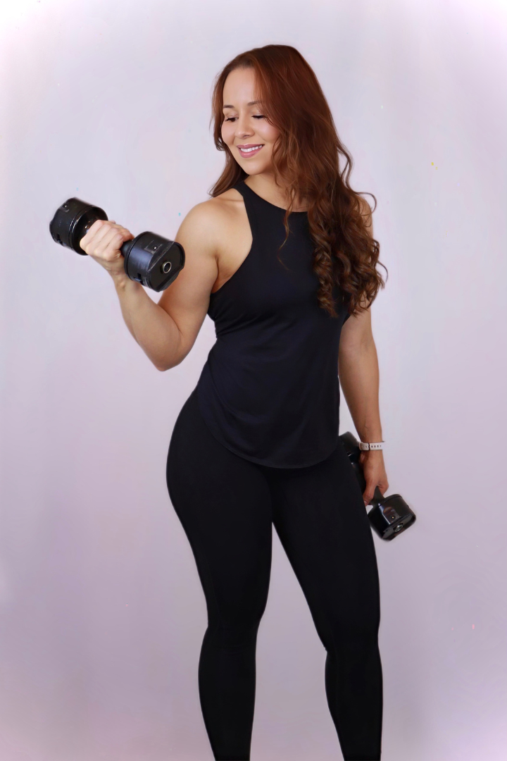 a woman in a black tank top is holding a dumbbell and smiling