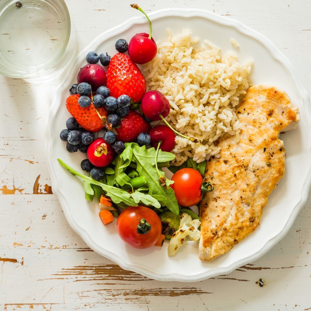 A plate of food with rice , strawberries , blueberries and tomatoes