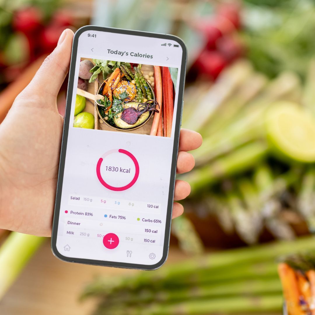 A person is holding a cell phone with a picture of vegetables on the screen