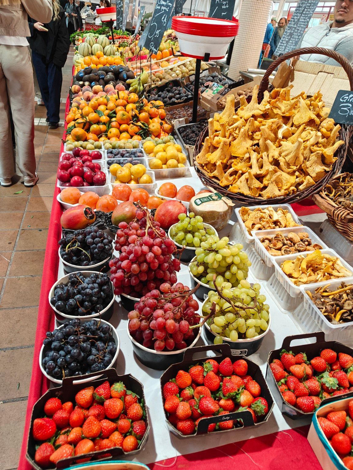 Fresh produce market in Europe with colorful grapes, strawberries, mushrooms, and citrus fruits