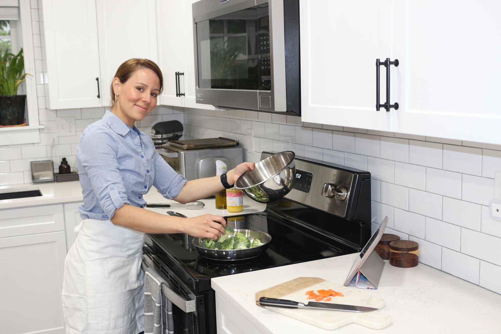 A woman is cooking in a kitchen and pouring vegetables into a pan.