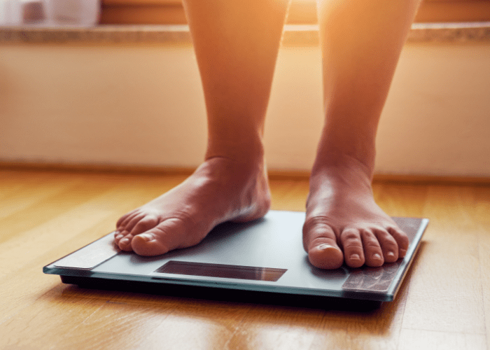 A person is standing on a scale on a wooden floor.