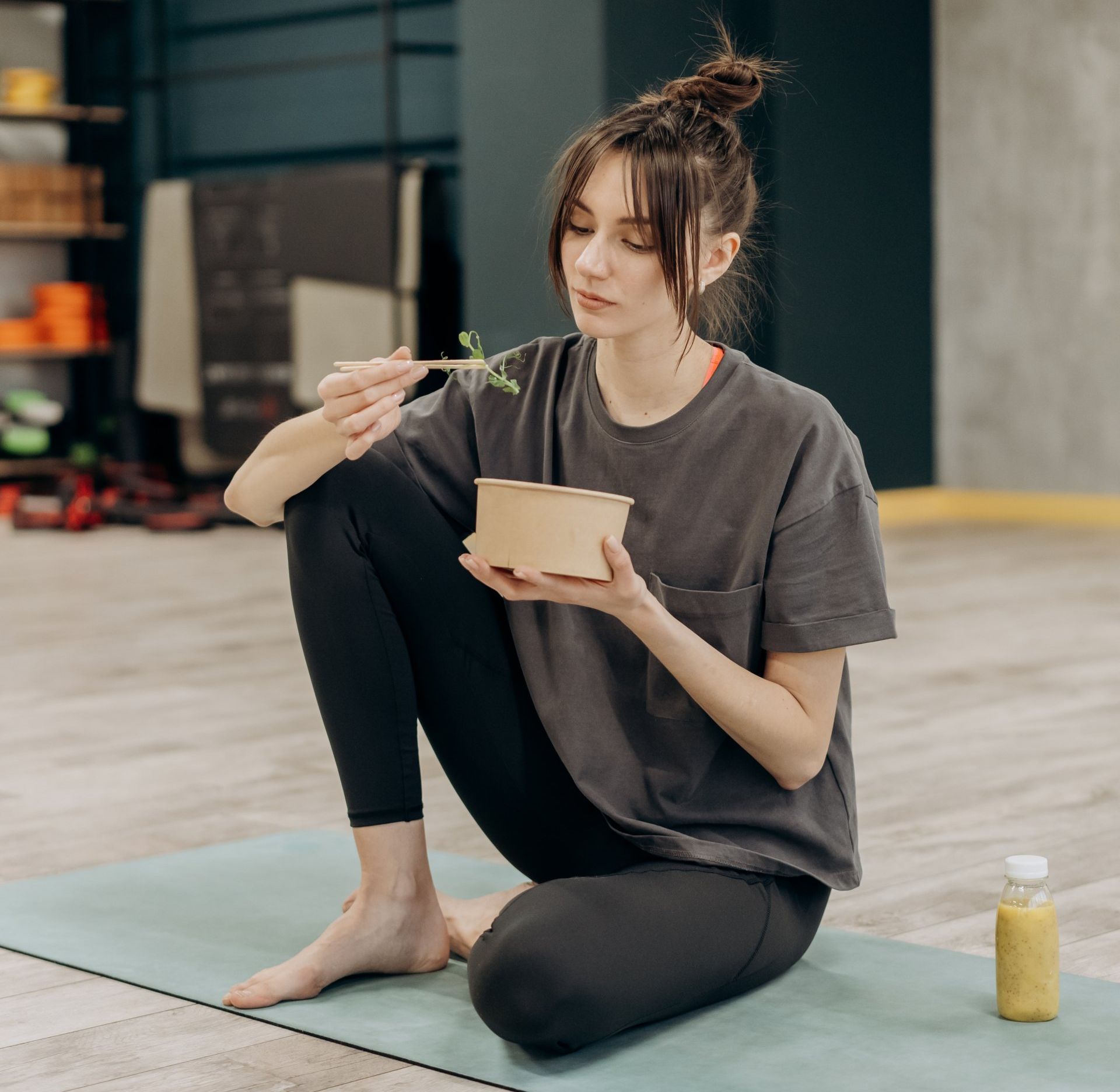 a woman is sitting on a yoga mat eating food .