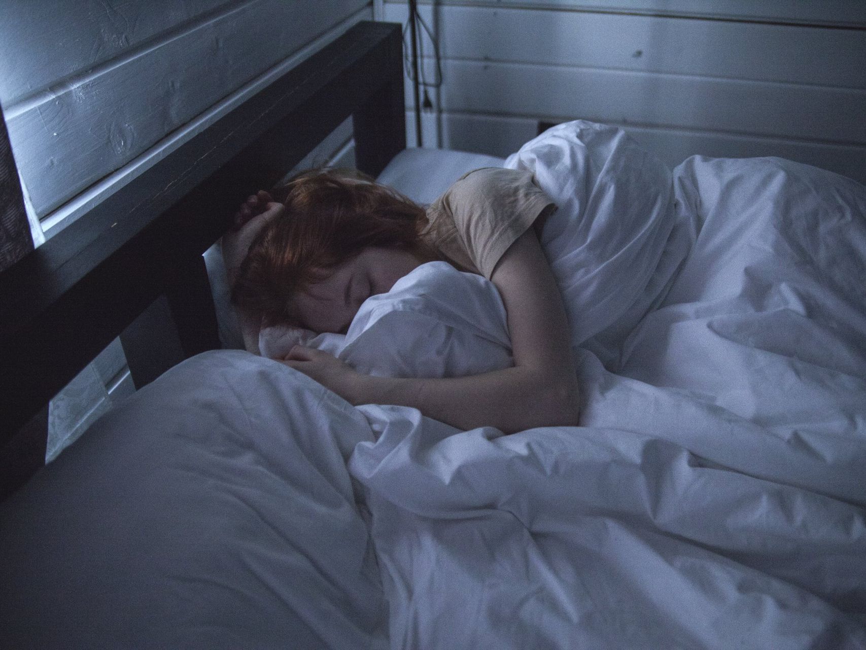 A woman is sleeping in a bed with white sheets.