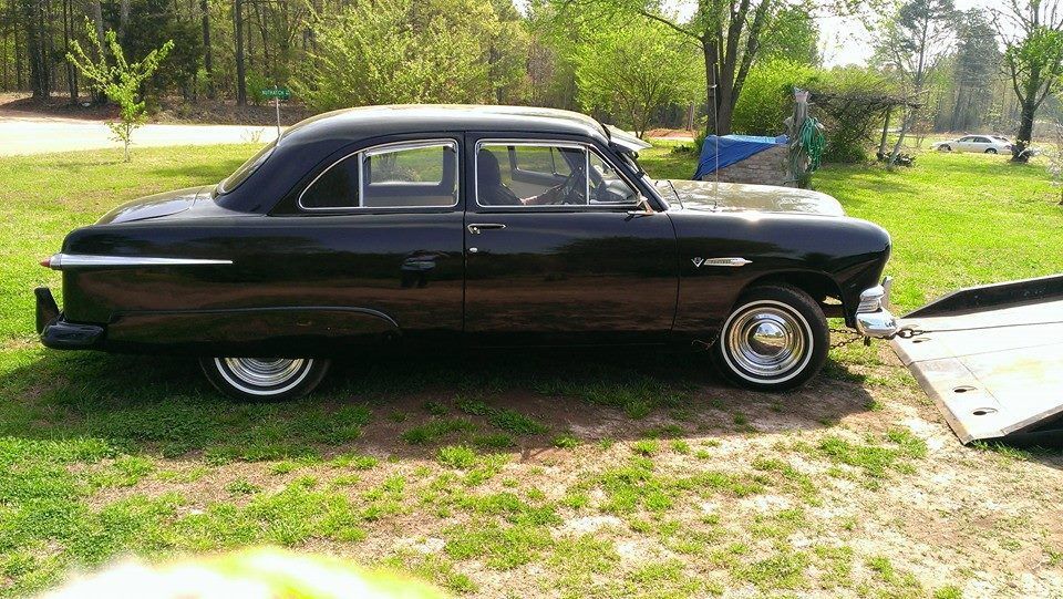 Black classic Ford sedan parked on grass.