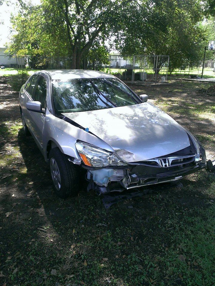 Silver Honda Accord with front-end damage parked on grass, under trees.