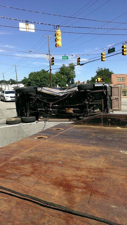 Truck overturned on a city street. Traffic lights overhead. Tires scattered.
