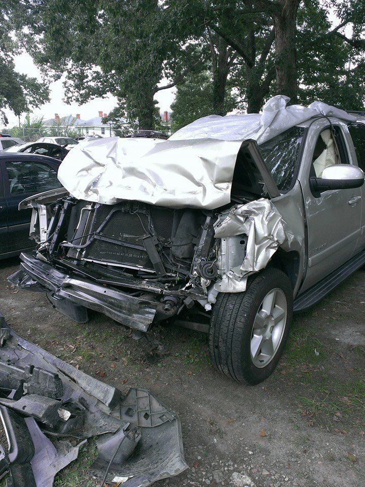 Damaged silver SUV with extensive front-end collision damage, parked outdoors.