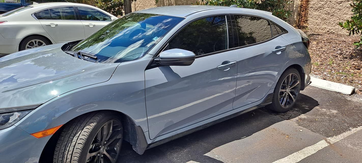 A gray Honda Civic hatchback parked outdoors on a sunny day.