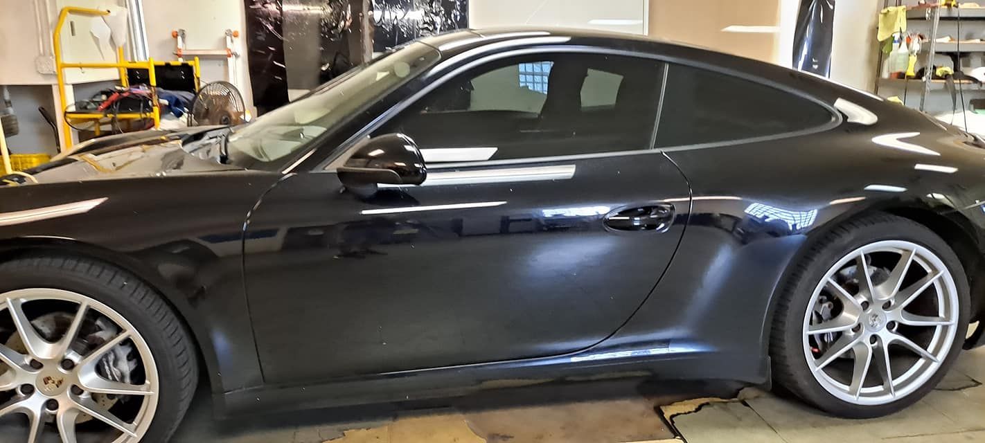 Black Porsche car with tinted windows parked in a garage.