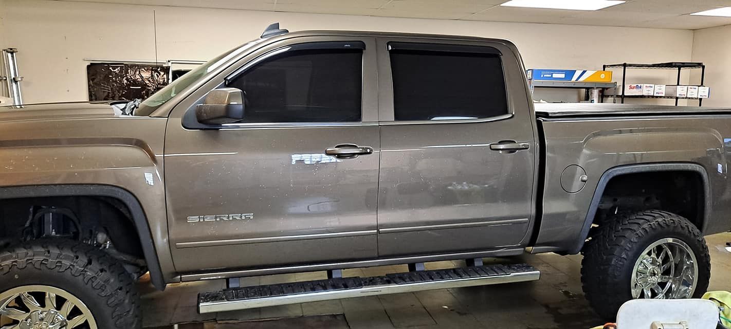 Brown GMC Sierra truck with tinted windows in a garage.