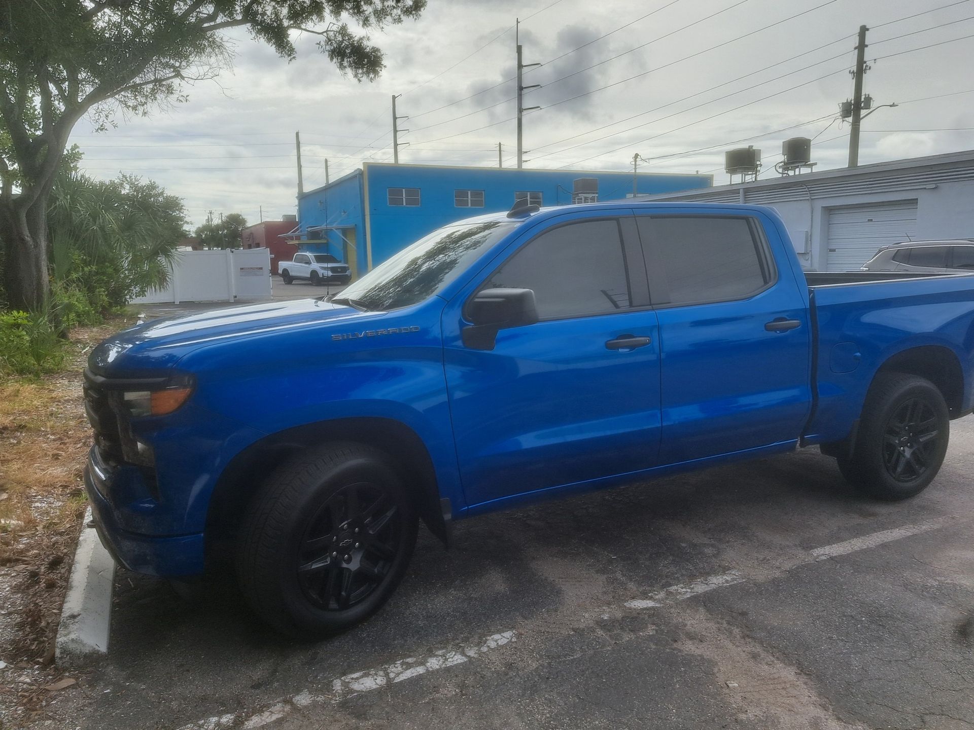 Blue Chevrolet Silverado pickup truck parked in a lot with black wheels and tinted windows.