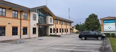 A tan and white building with a dark car parked in front. A sign for Innovative Health is on the right.