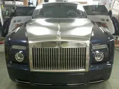 Dark blue Rolls Royce with a silver hood and grille, doors open in a garage.