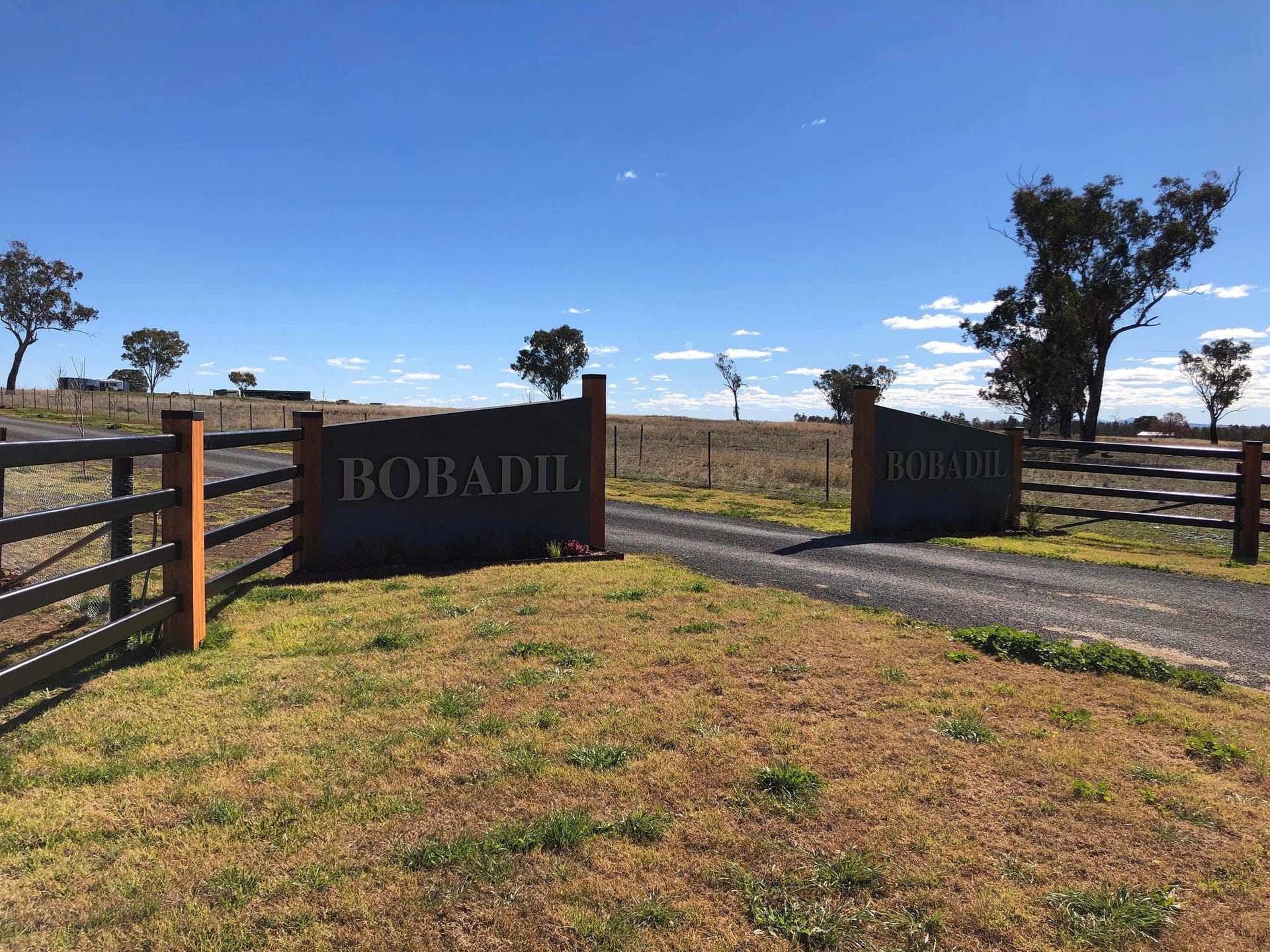 A gravel driveway entrance framed by two dark stone pillars labeled