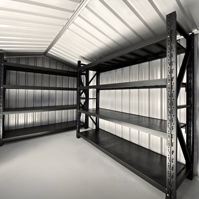 Two black, multi-tier metal storage shelving units installed in a corner of a corrugated metal-walled shed.