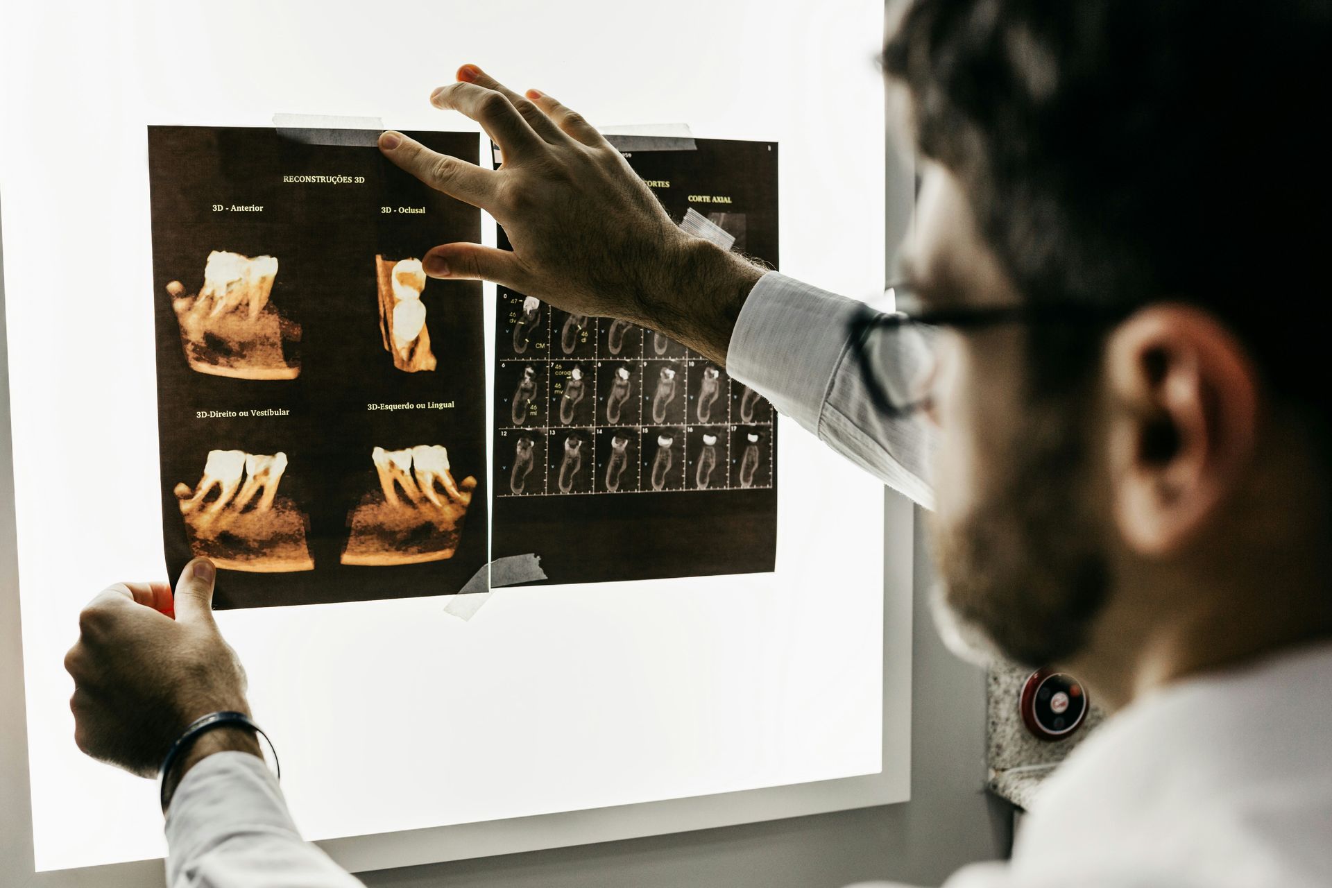 Dentist examining dental X-rays on a lit screen, diagnosing.