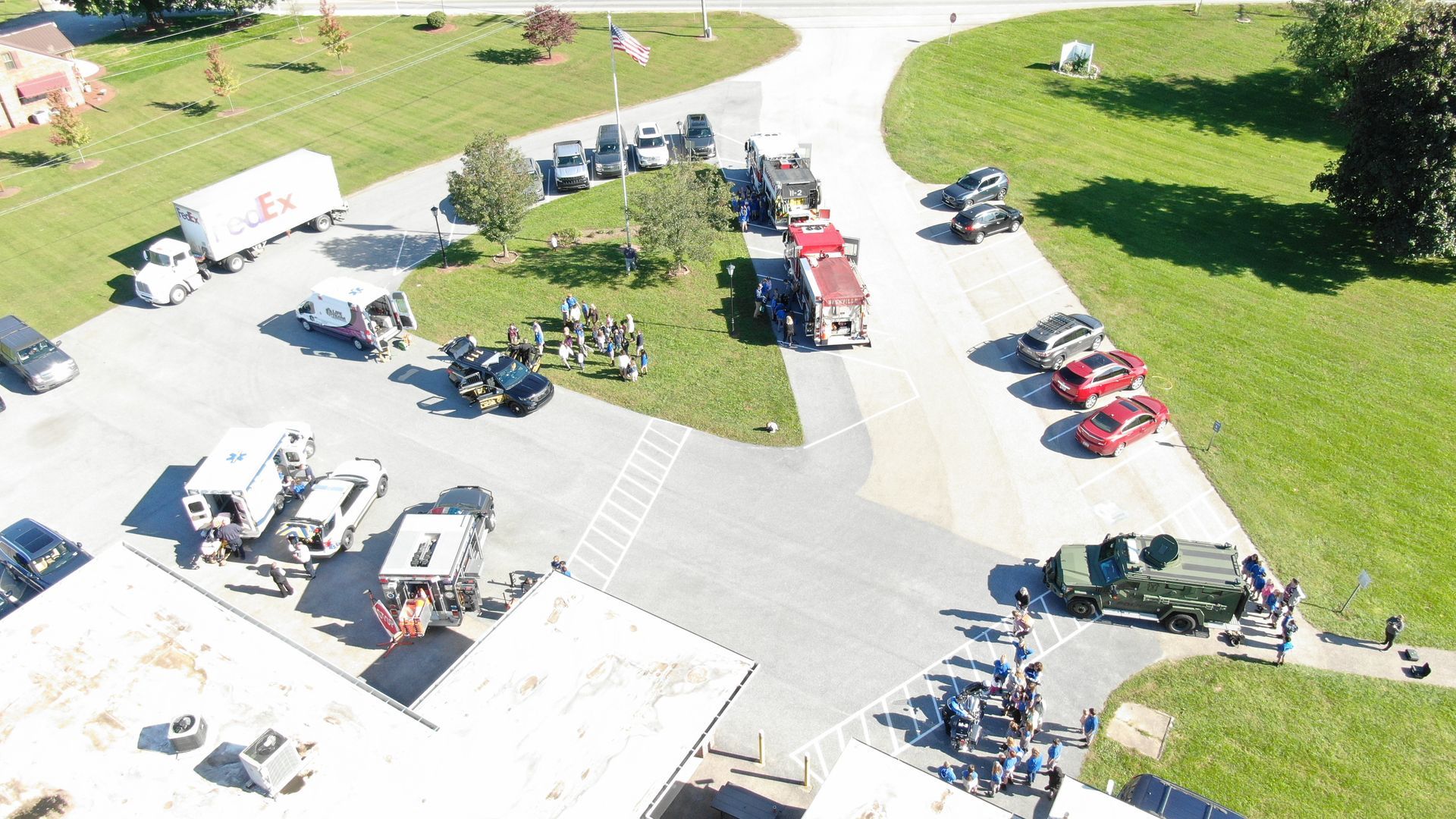 Aerial view of trucks and cars parked outside a building on a sunny day.