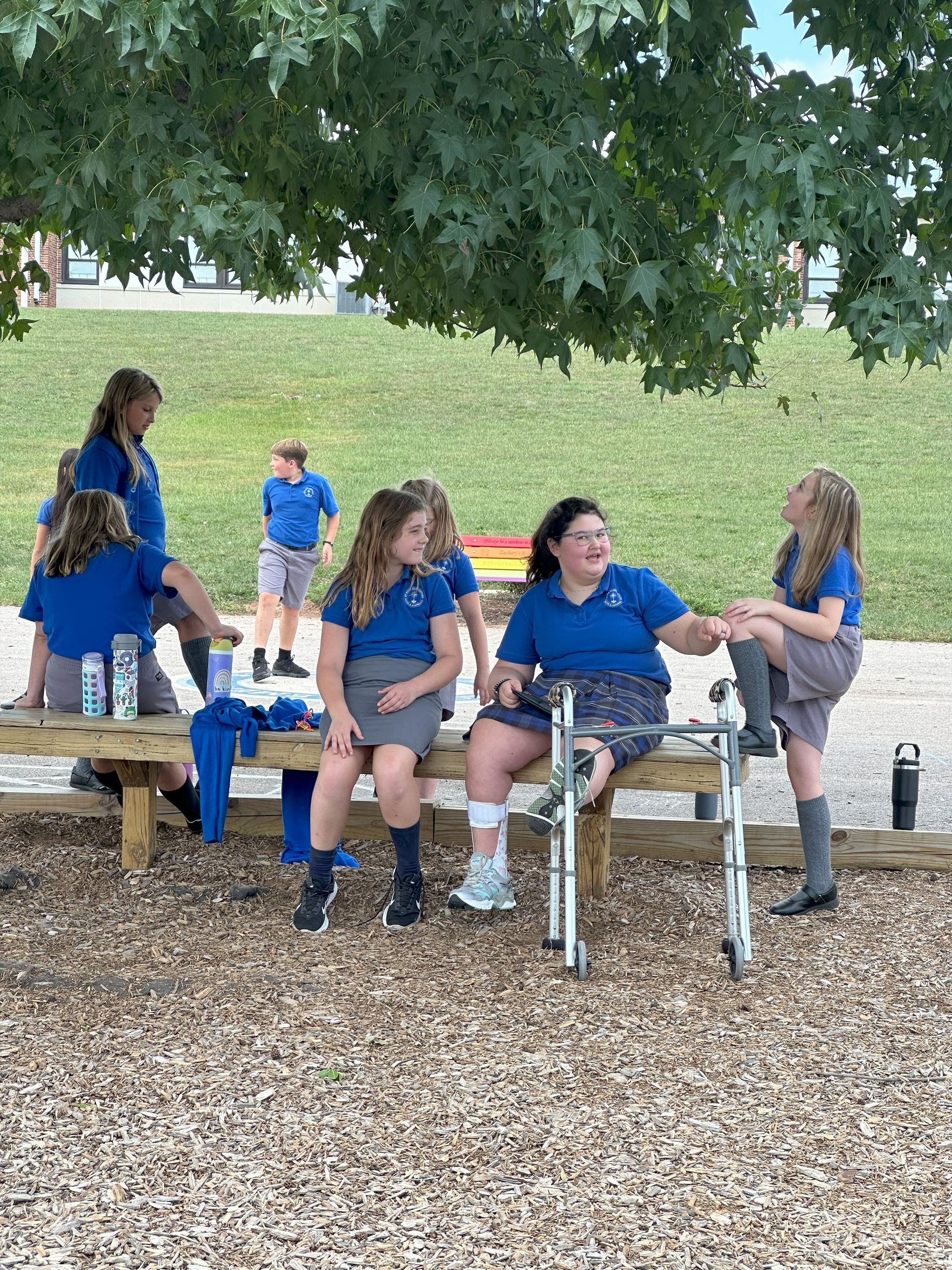 Three children are sitting on a playground with their arms in the air