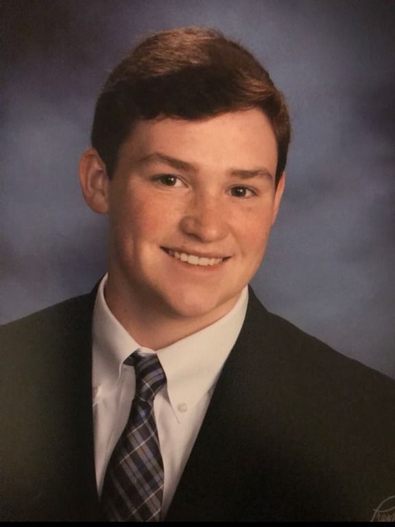 A young man in a suit and tie smiles for the camera