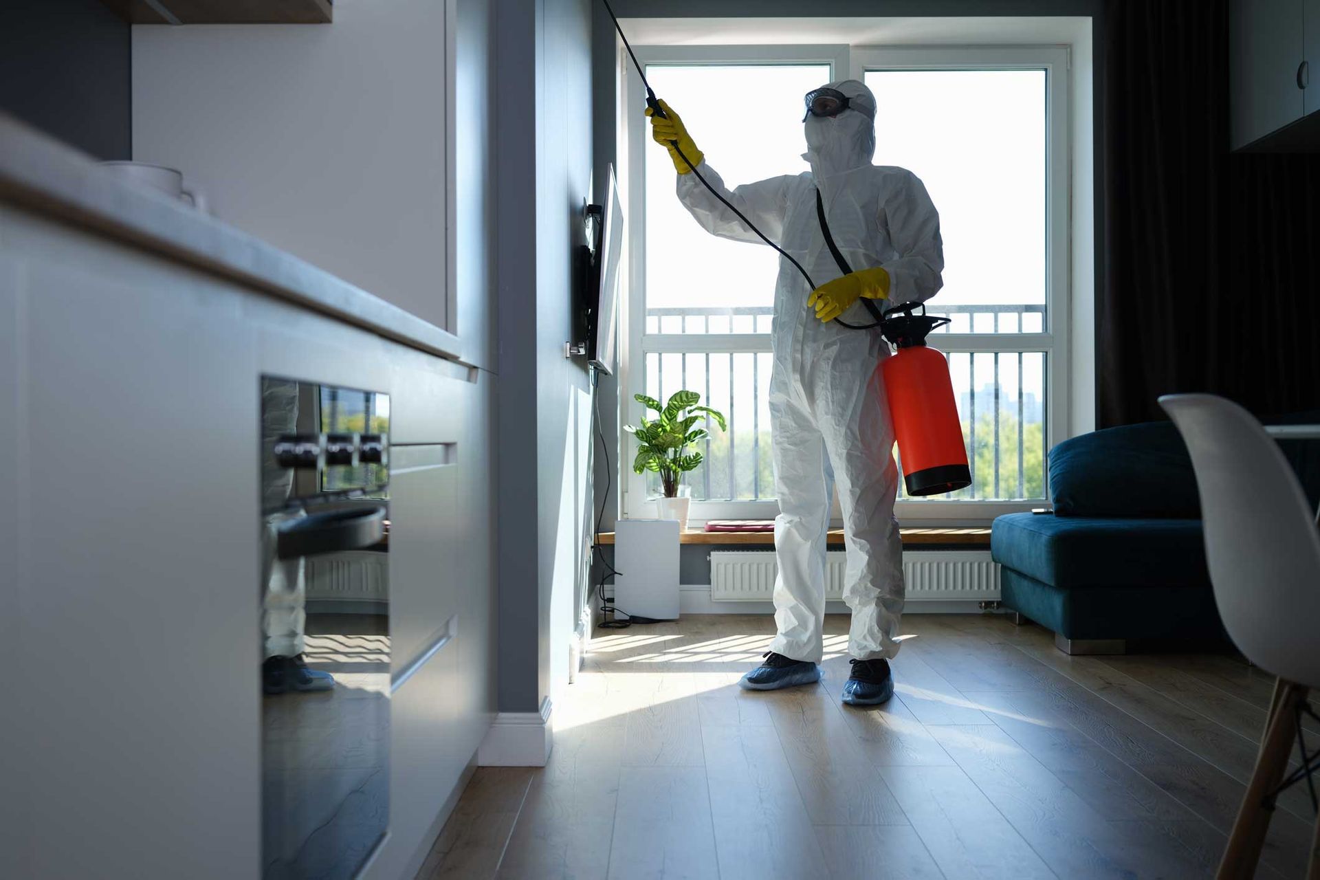 Person in white protective suit spraying disinfectant in a modern living room near a window Person in white protective suit spraying disinfectant in a modern living room near a window