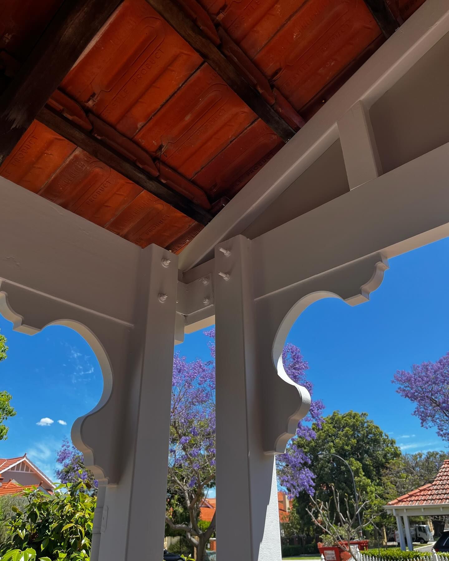 Looking up at the roof of a gazebo with purple flowers in the background