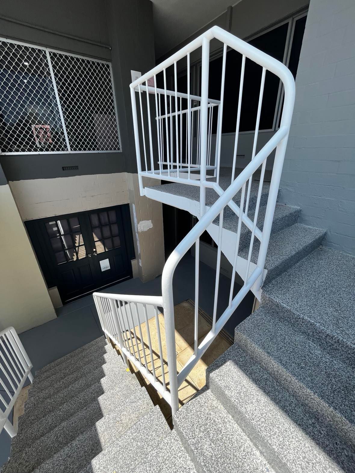 A spiral staircase with a white railing in a building.