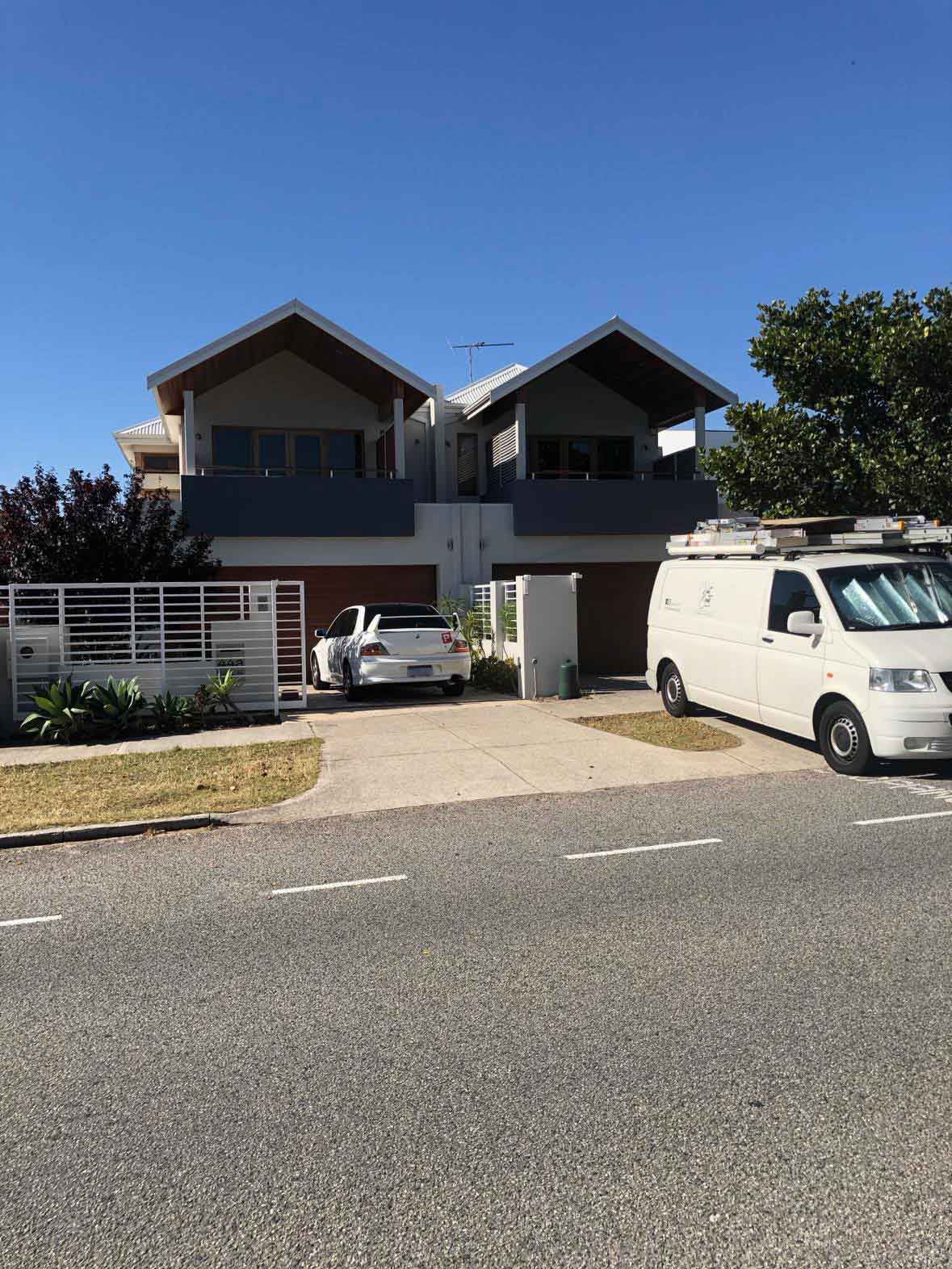 A white van is parked in front of a large house.