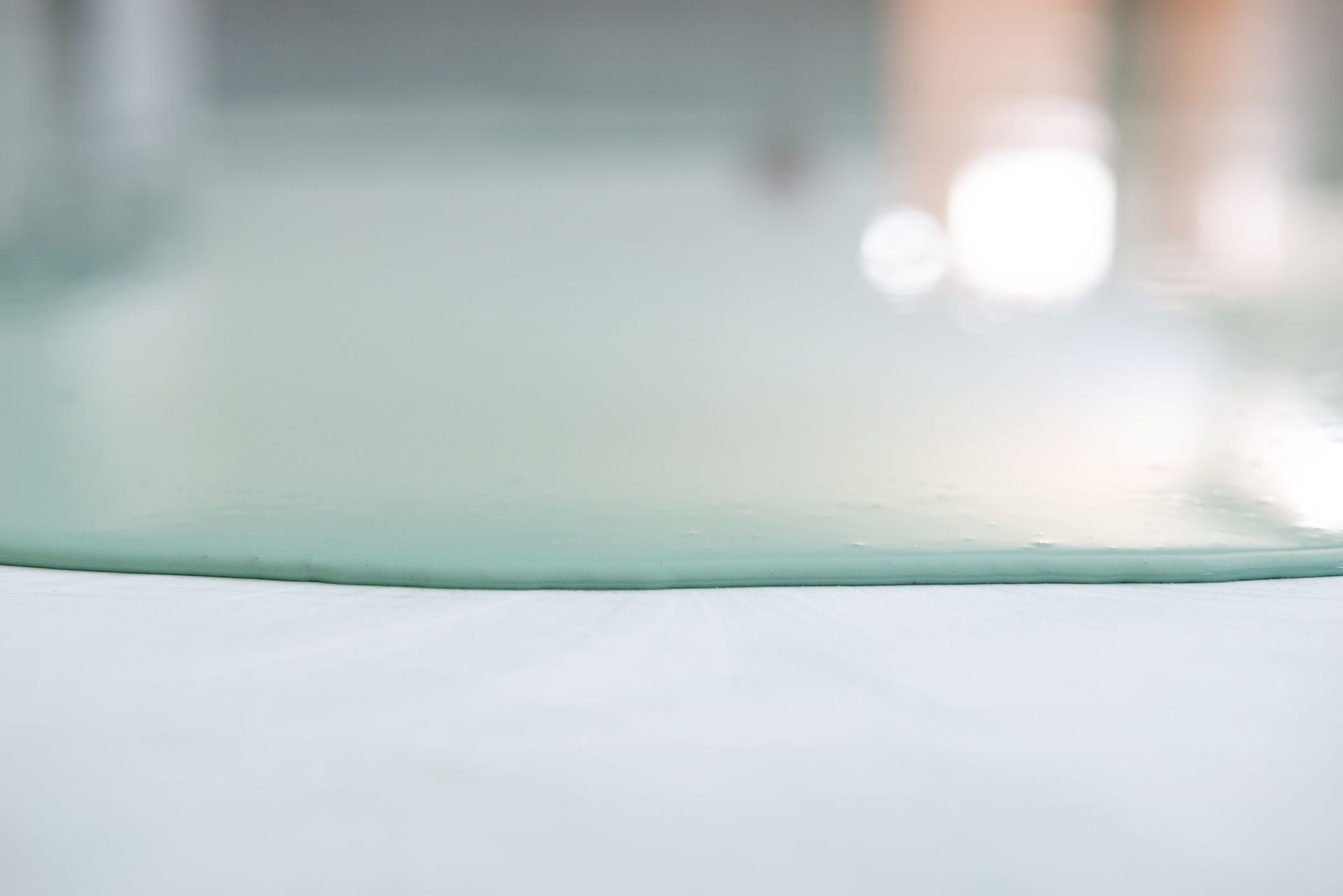 A close-up of pastel green epoxy being poured on the ground.