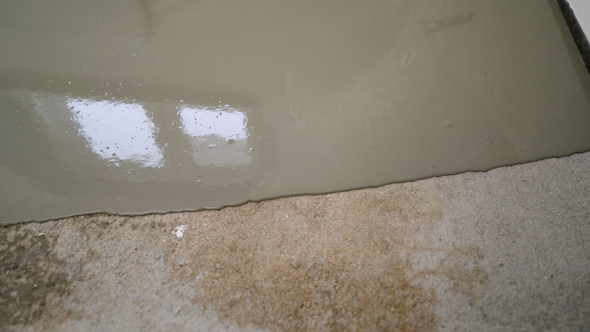 Workers applying epoxy resin on a concrete surface.