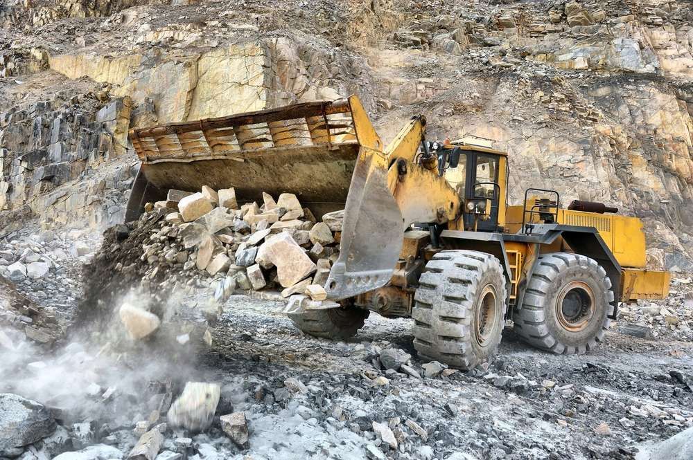 A Bulldozer is Loading Rocks Into a Truck in a Quarry — Rowdraulics NQ Pty Ltd In Mount Louisa, QLD