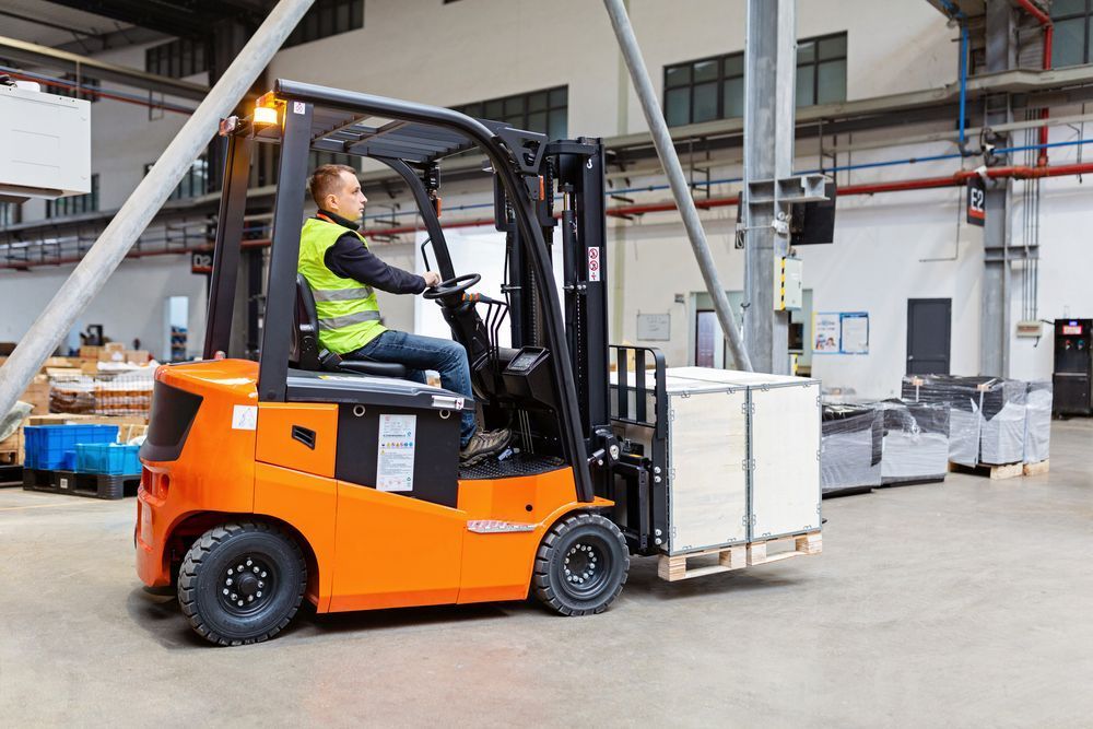 A Man is Driving a Forklift in a Warehouse — Rowdraulics NQ Pty Ltd in Mount Louisa, QLD