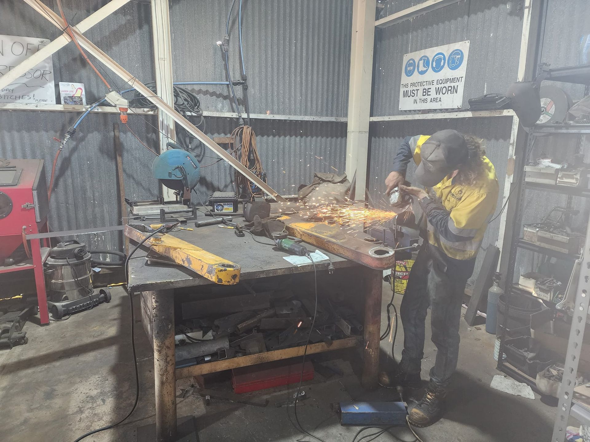 Man Working On A Part Of Excavator  In A Workshop — Rowdraulics NQ Pty Ltd in Mackay, QLD