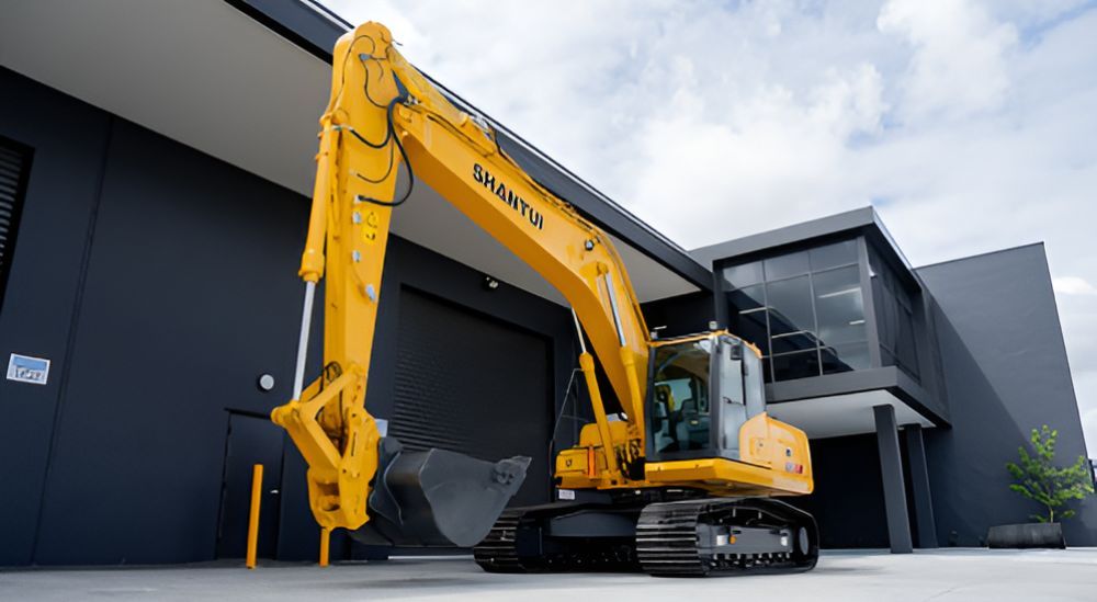 A Yellow Excavator is Parked in Front of a Building — Rowdraulics NQ Pty Ltd in Mount Louisa, QLD