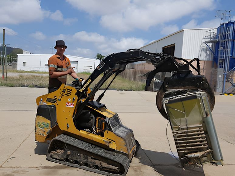 A Man is Standing Next to a Small Yellow Tractor — Rowdraulics NQ Pty Ltd In Mount Louisa, QLD