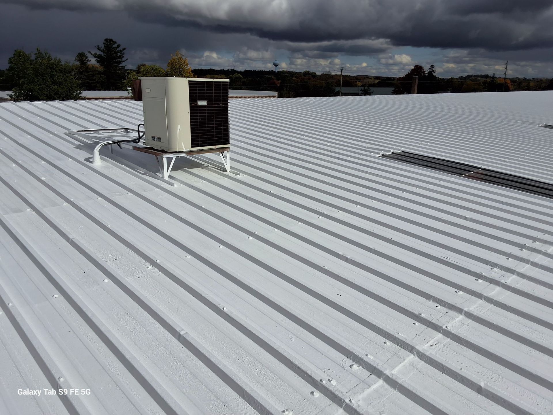 A white roof with a large air conditioner on top of it.