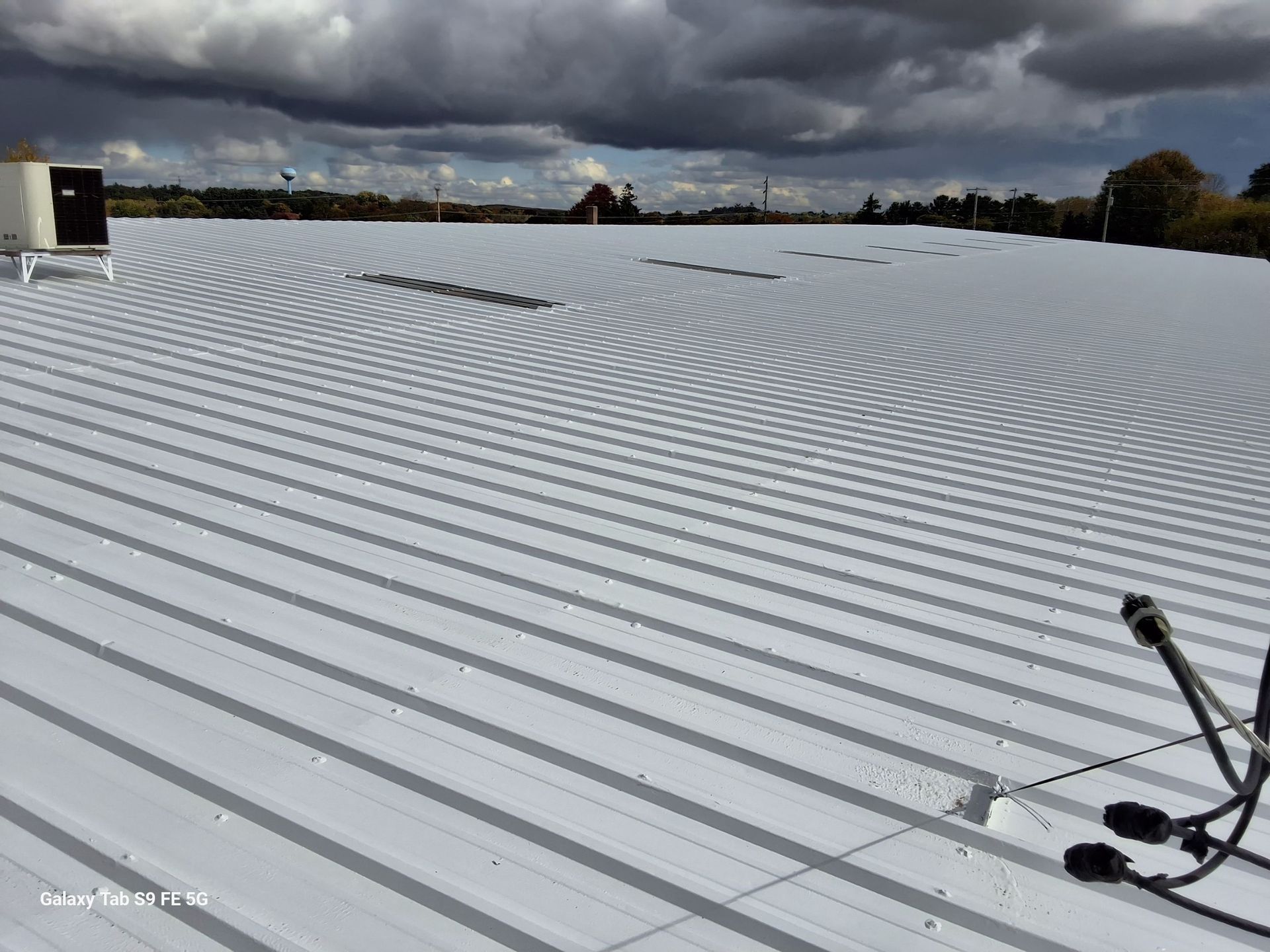 A white roof with a microphone on it and a cloudy sky in the background.